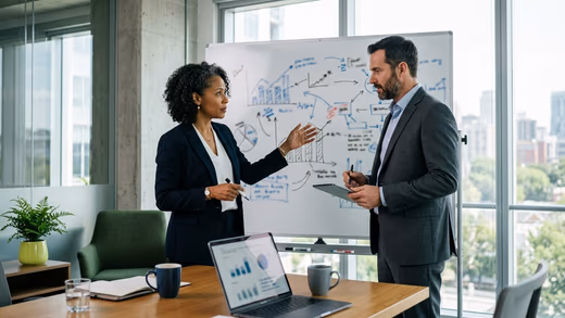 Une directrice financière et un directeur marketing discutent devant un tableau blanc couvert de graphiques