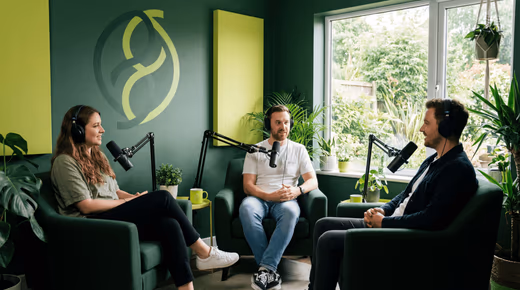 Trois personnes en fauteuil, casque sur les oreilles et micro sur bras, discutent dans un studio aux murs verts